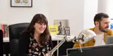 Darren and Lydia , the founders of Braw Talent shown smiling and working at their desk in their office.